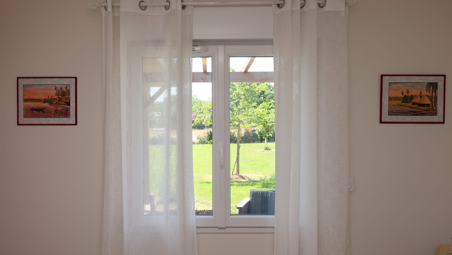 Vue intérieure d'une fenêtre aluminium blanche donnant sur le jardin