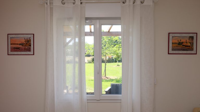 Vue intérieure d'une fenêtre aluminium blanche donnant sur le jardin