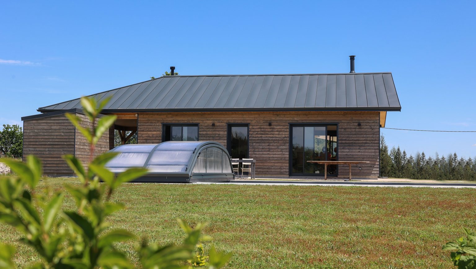 Façade arrière d'une maison ossature bois avec piscine couverte