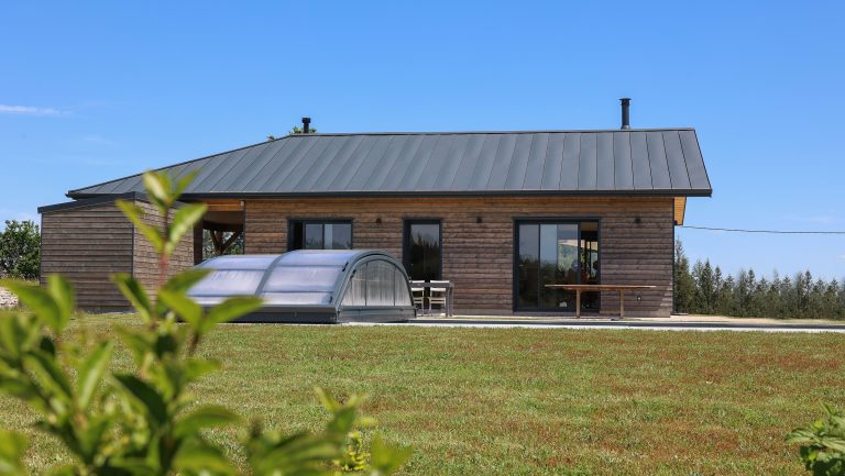 Façade arrière d'une maison ossature bois avec piscine couverte